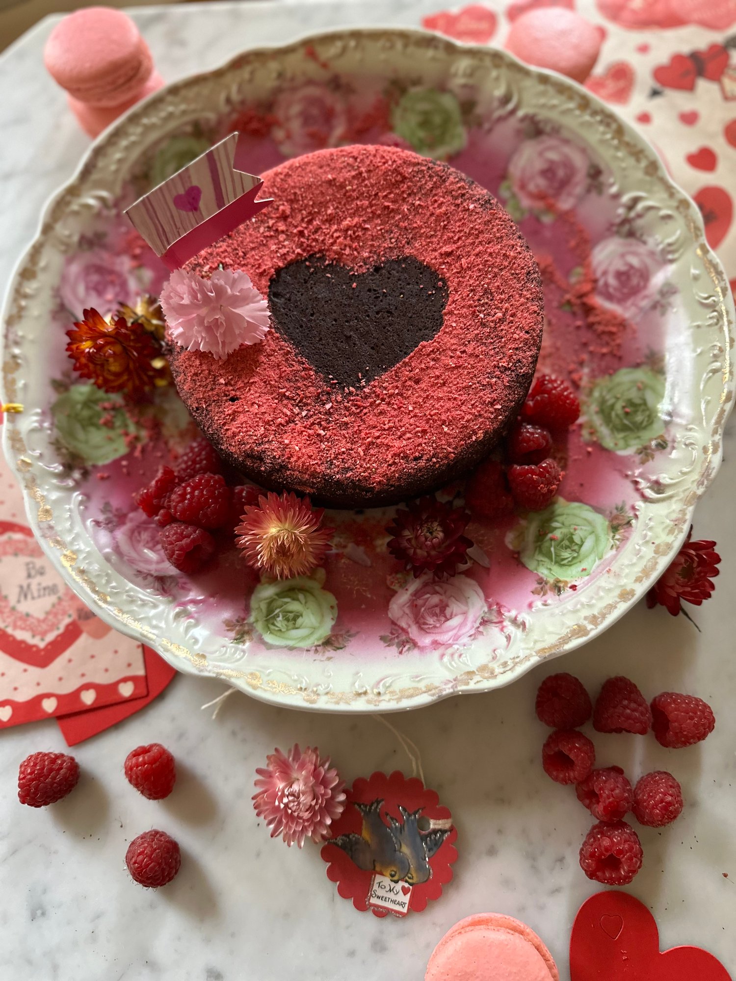 Flourless chocolate cake decorated with a heart, raspberries, and flowers