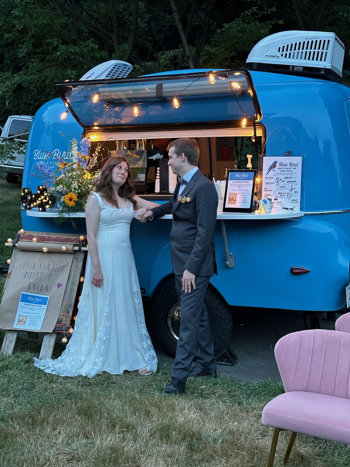 Bride and groom holding hands in front of the Blue Bird camper